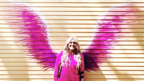 posing front of wings painted on a wall